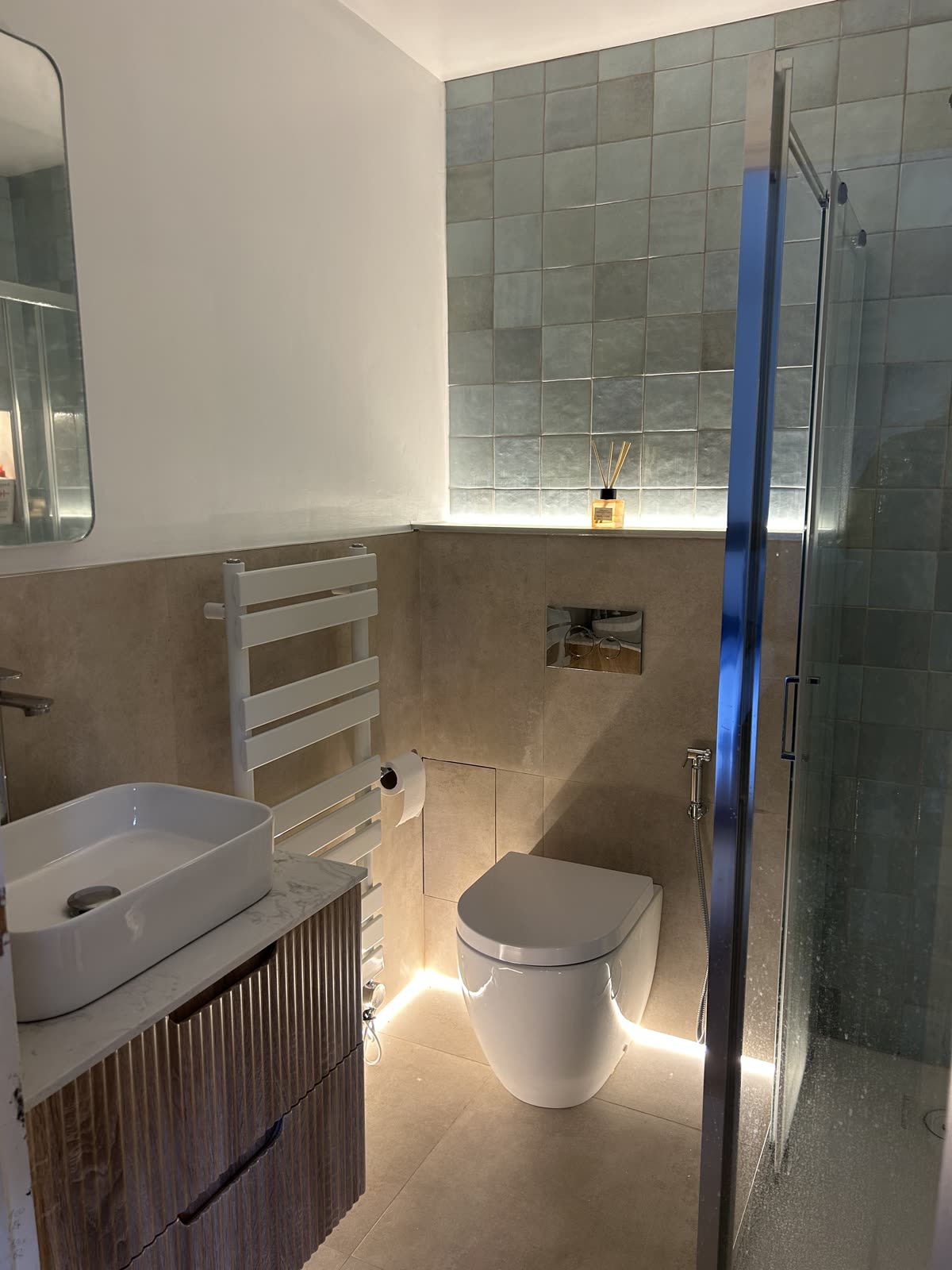 Compact bathroom with a walk-in shower, fluted vanity and backlit niche