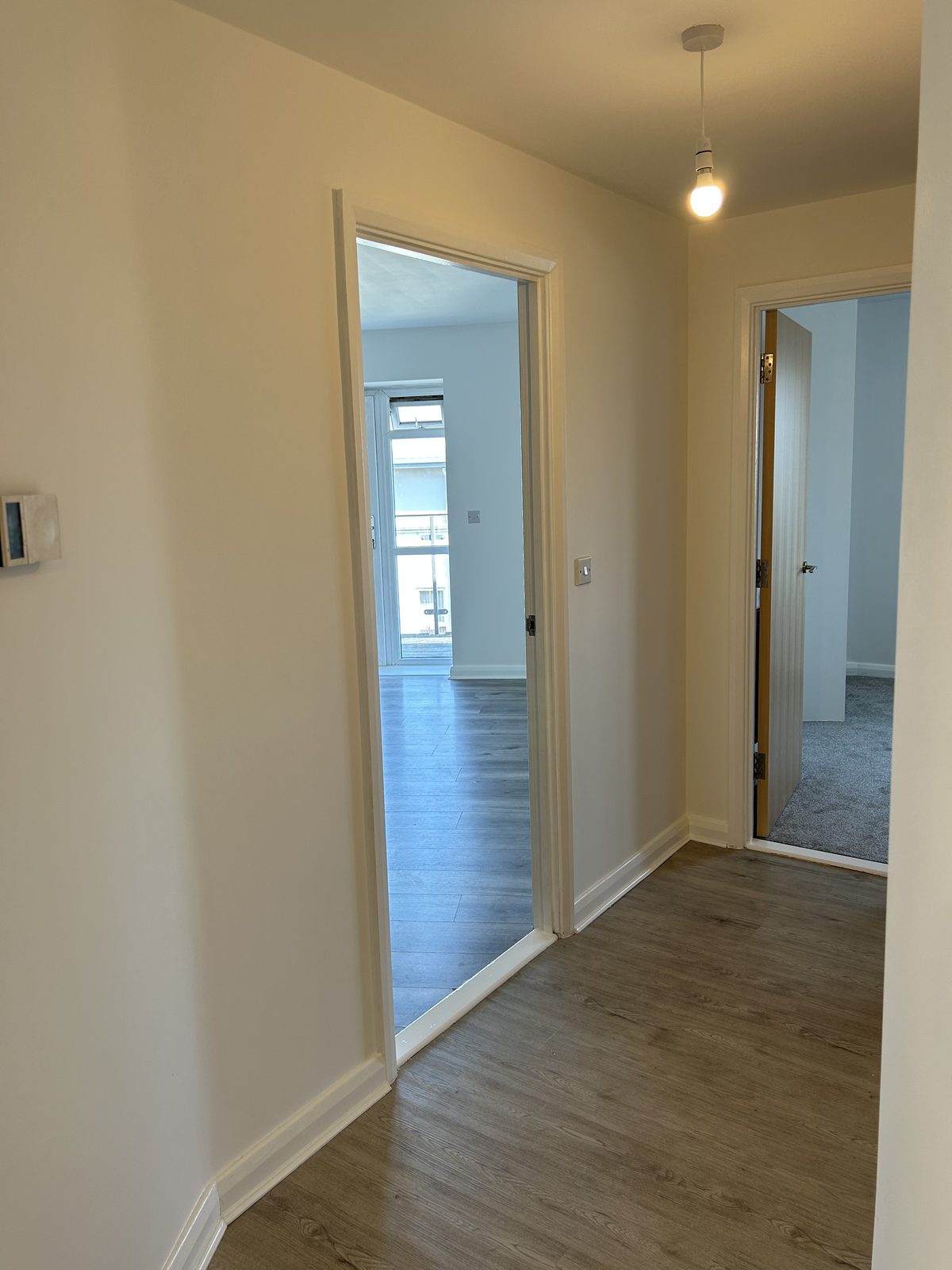 Refurbished hallway with new wood-effect plank flooring and doorways through to the rooms