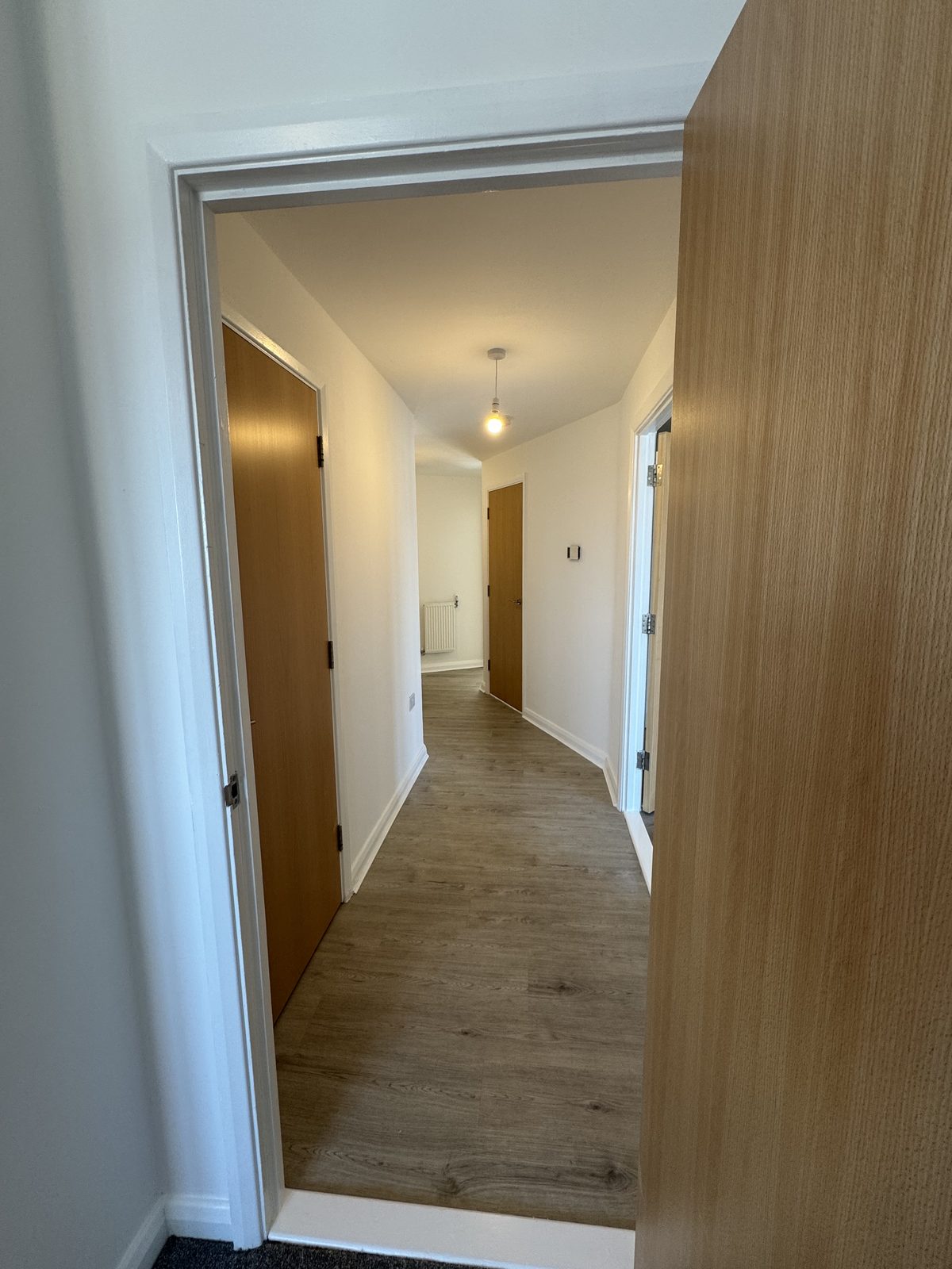 New wood-effect flooring and oak-veneer doors through the hallway