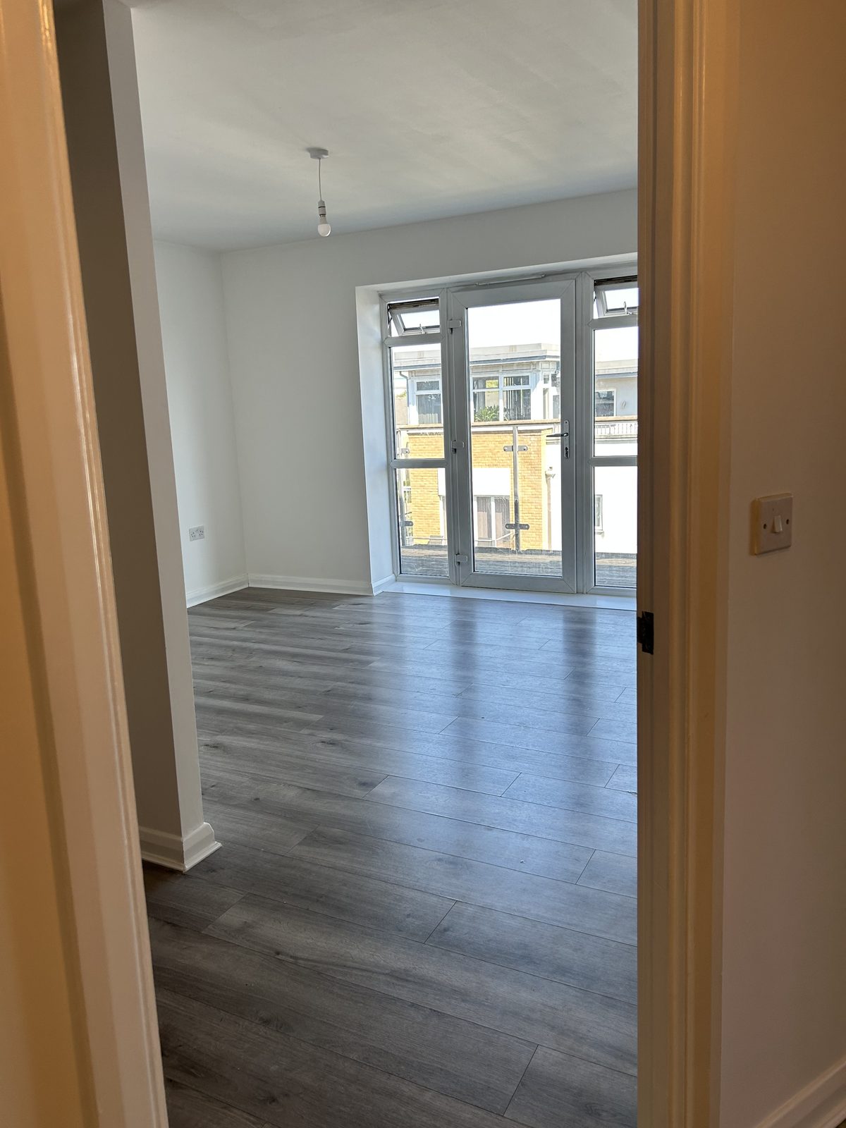 Refurbished room with new wood-effect plank flooring and freshly painted walls