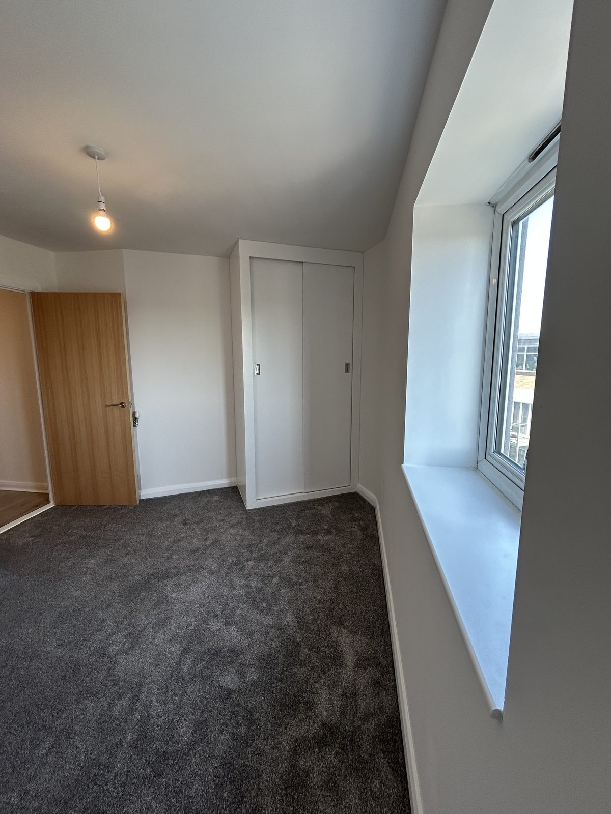 Refurbished bedroom with a fitted wardrobe, new carpet and a deep window reveal