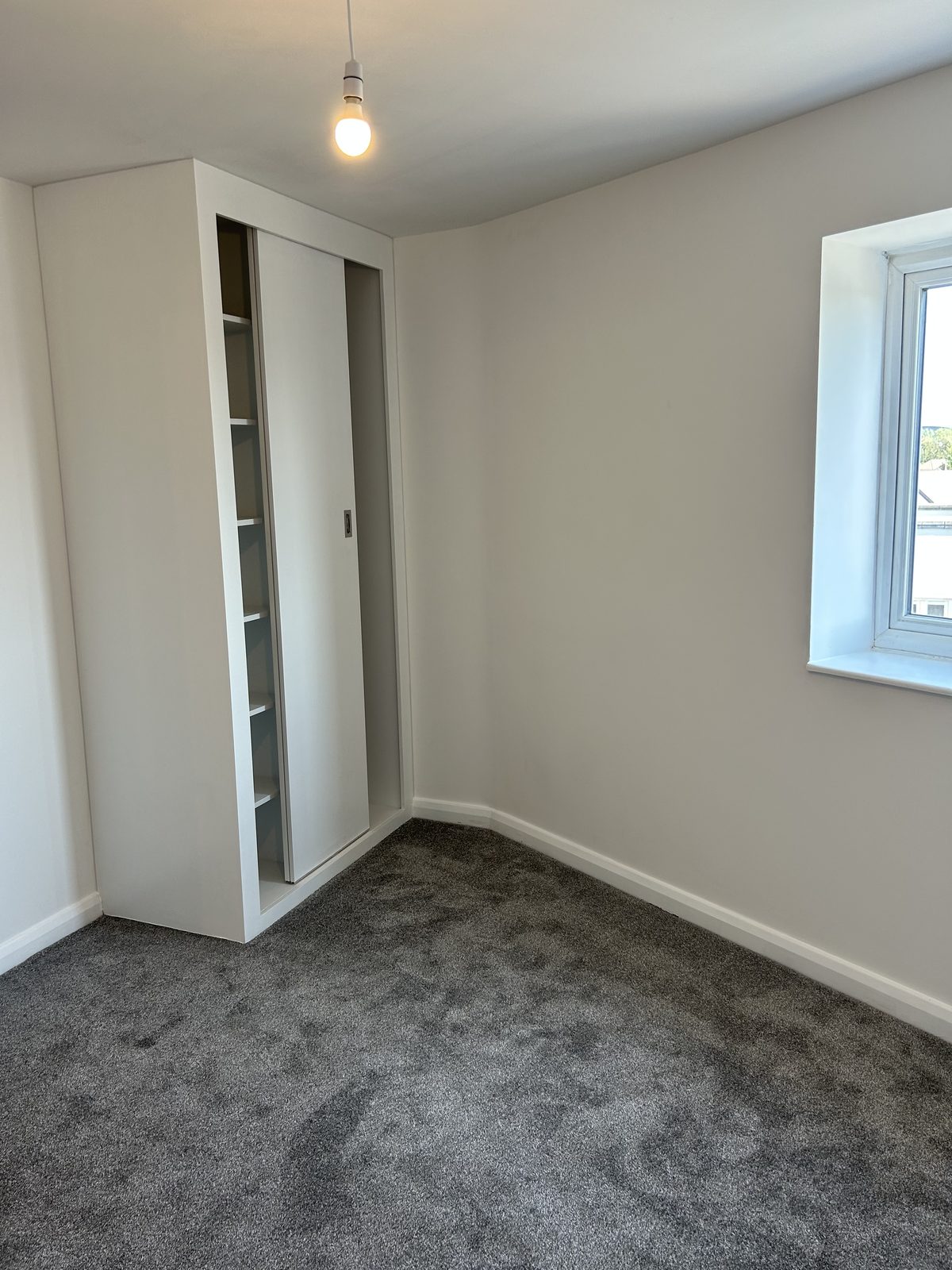 Fitted wardrobe with a sliding door and an open shelving column built into the corner