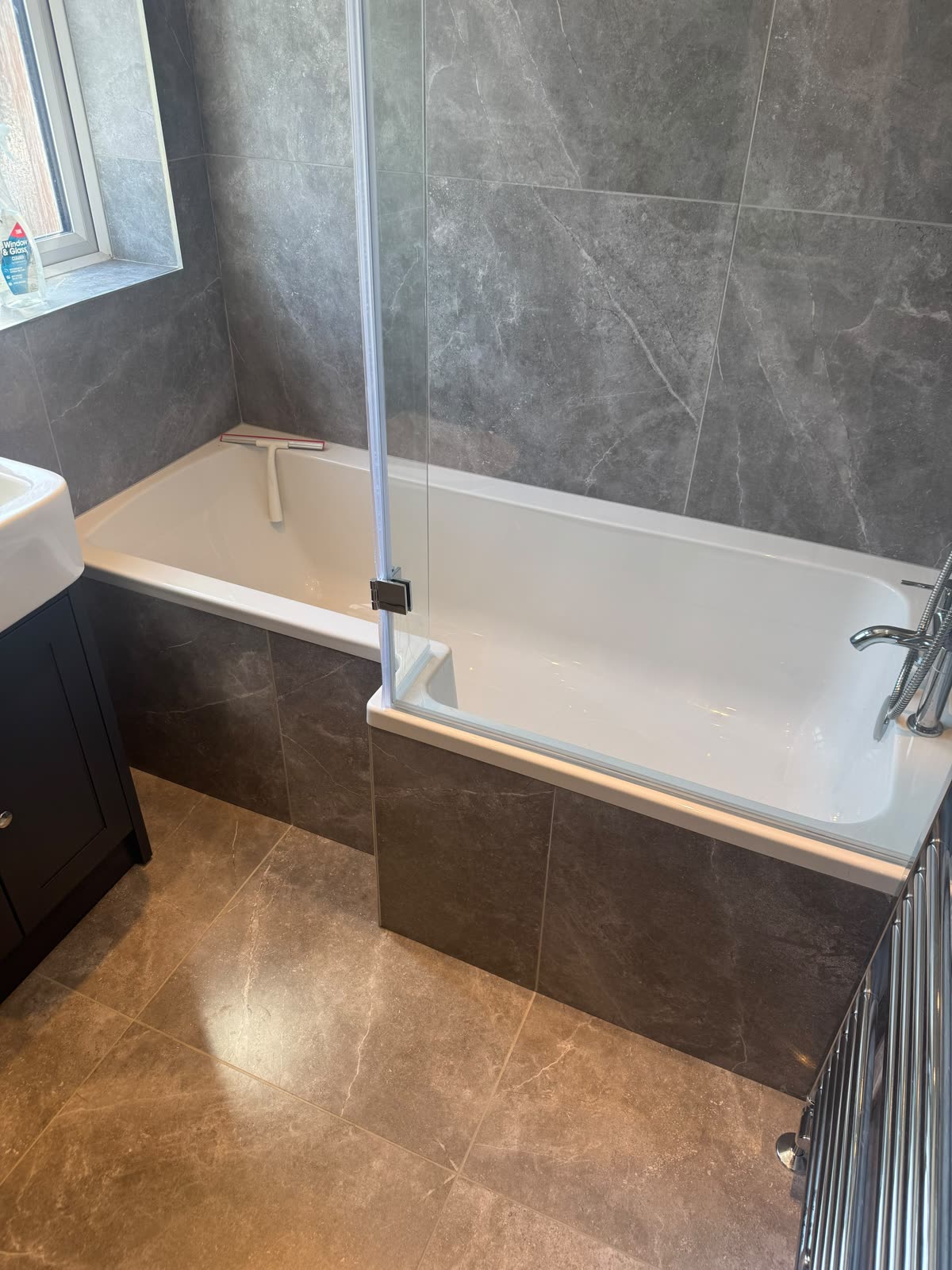 Bath and marble-effect tiling above a stone-effect tiled floor