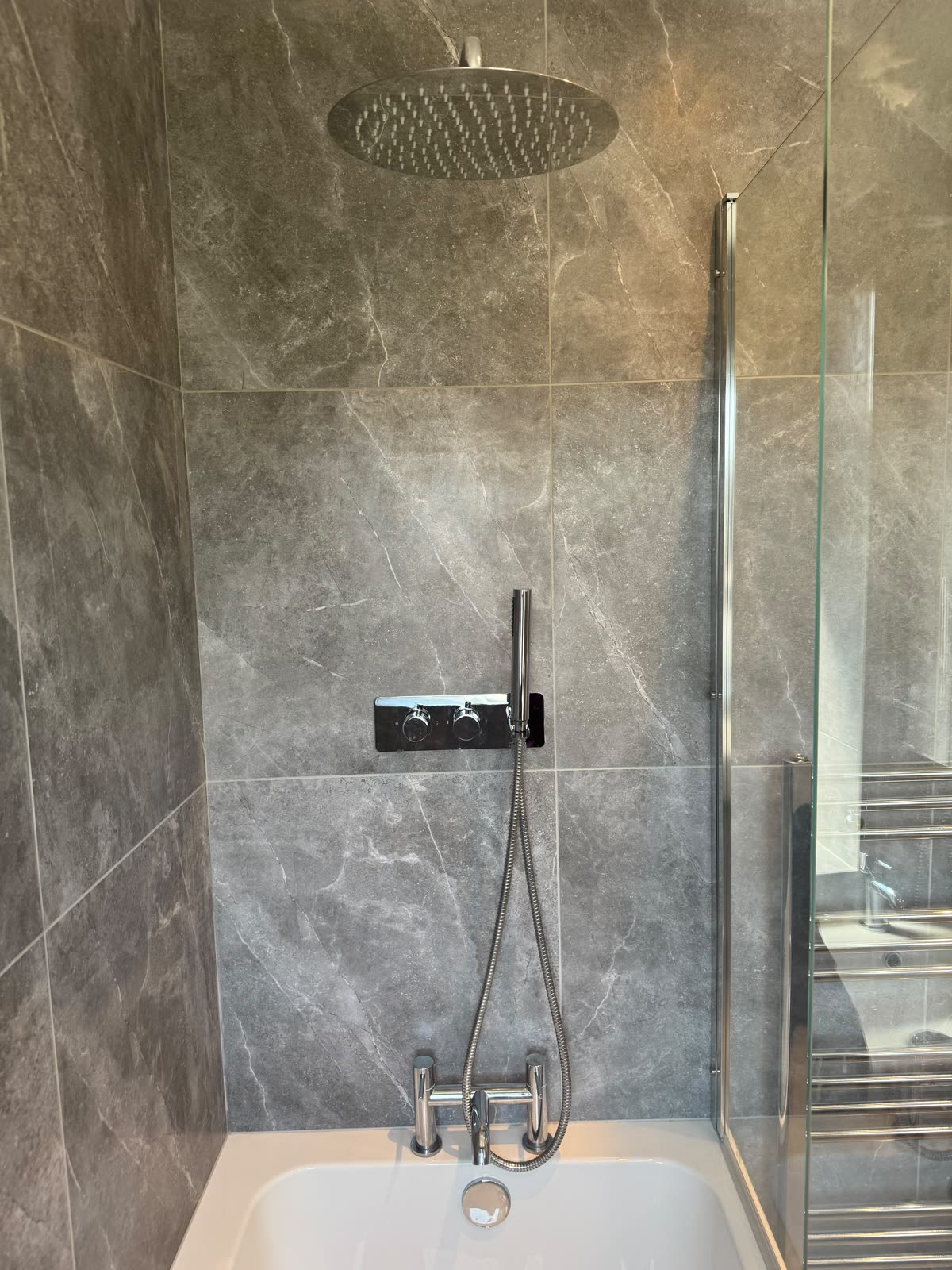 Rainfall shower head and thermostatic valve on marble-effect tiling