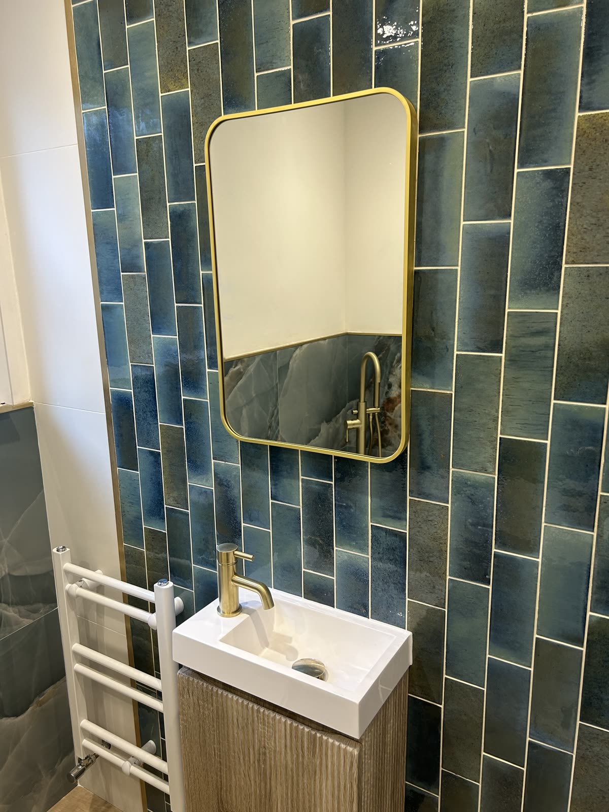 Fluted vanity unit and brass tap below a brass-framed mirror