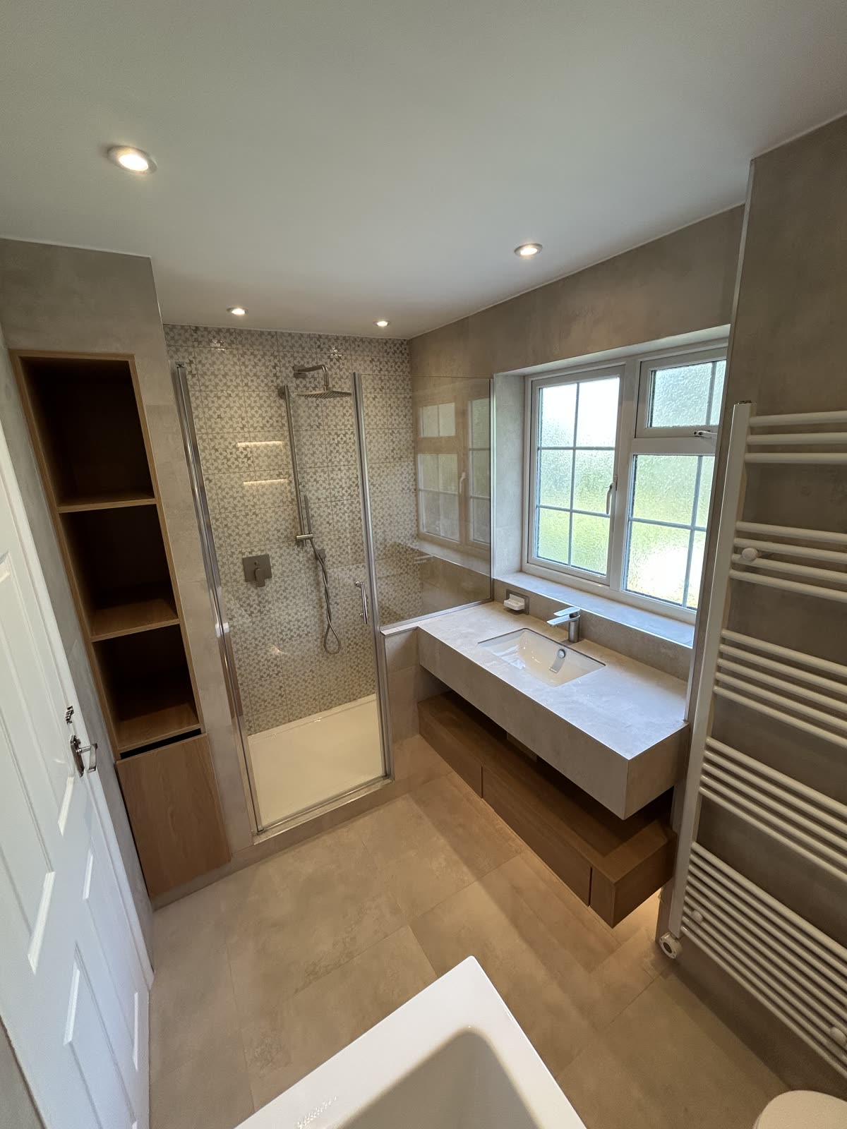 Bathroom with walk-in shower, floating stone vanity and full-height oak storage tower