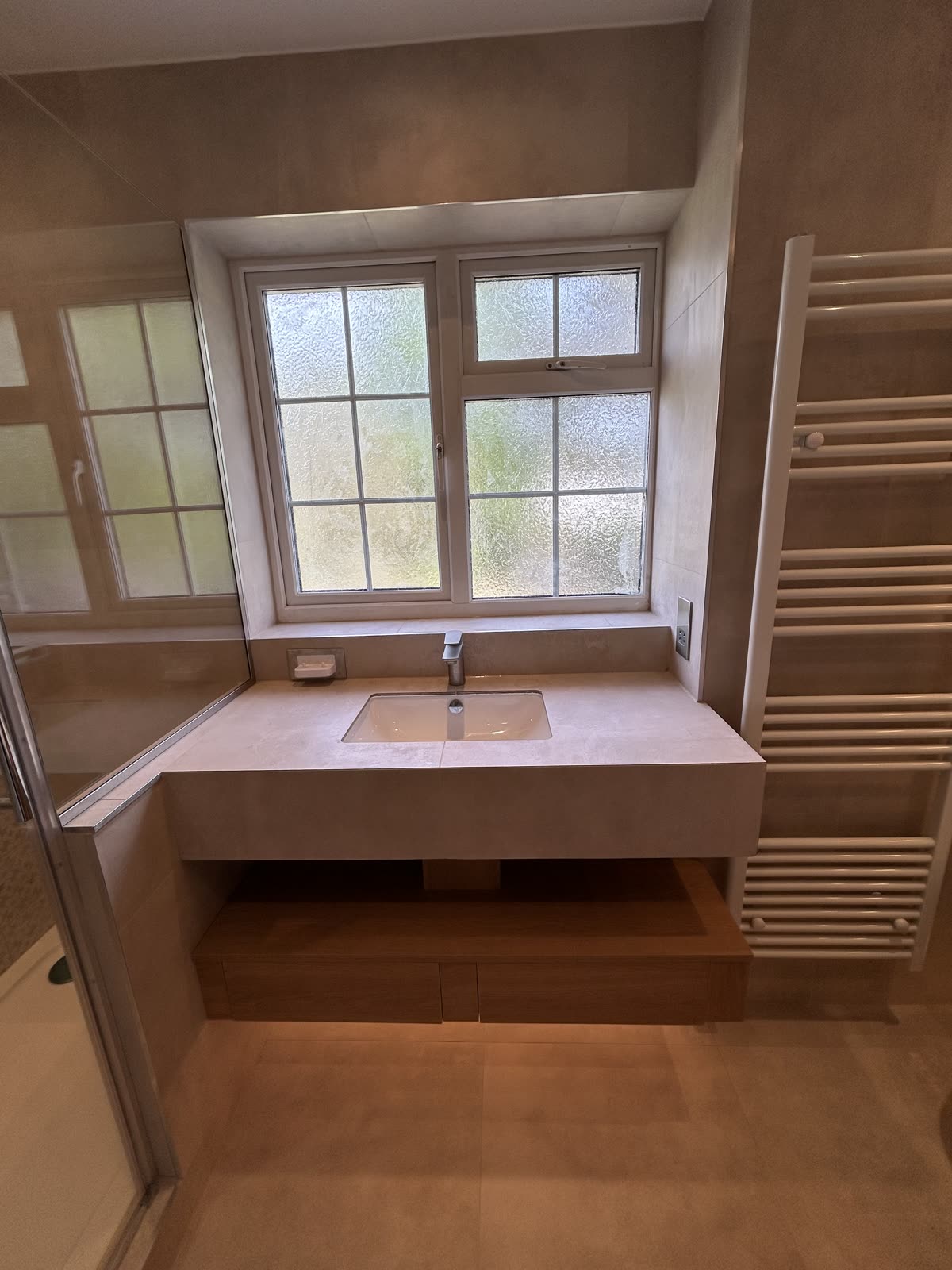 Floating stone vanity with undermounted basin set below a window