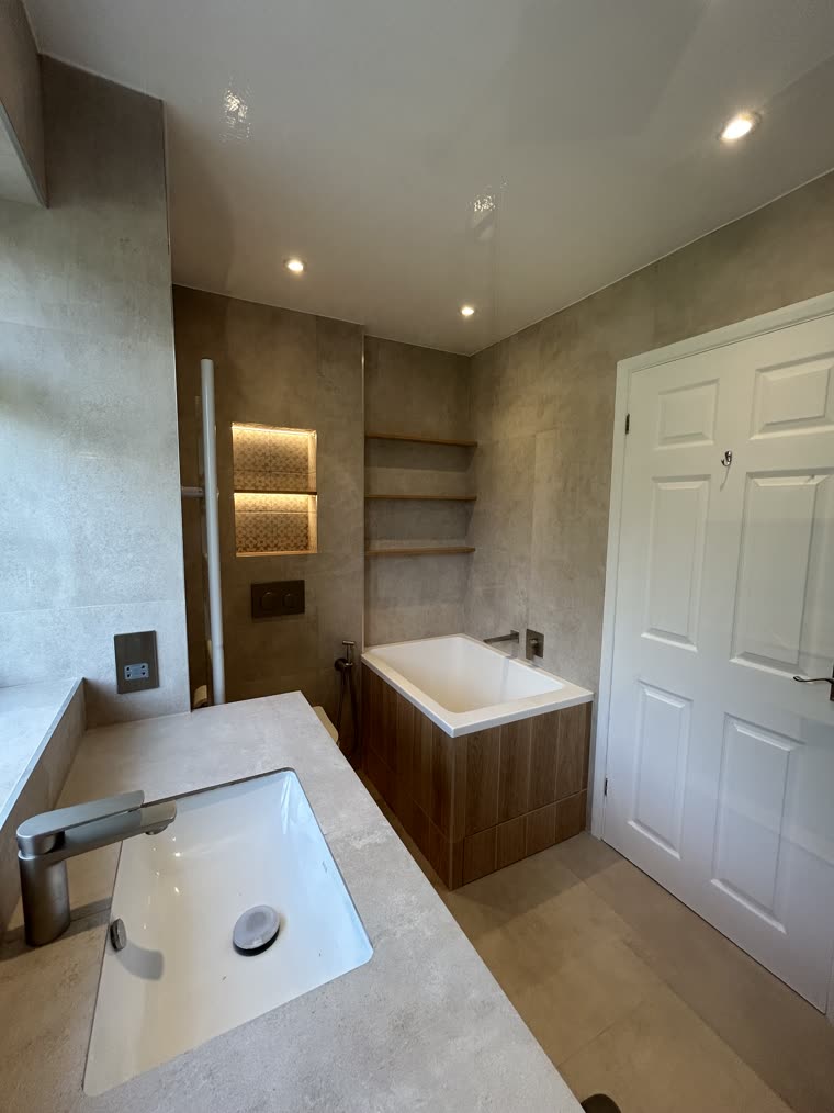 Stone-topped vanity and walnut-panelled bath beneath backlit niches