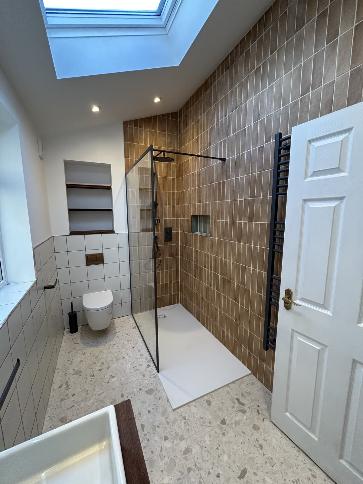 Loft bathroom under a roof window with a walk-in shower and terrazzo floor