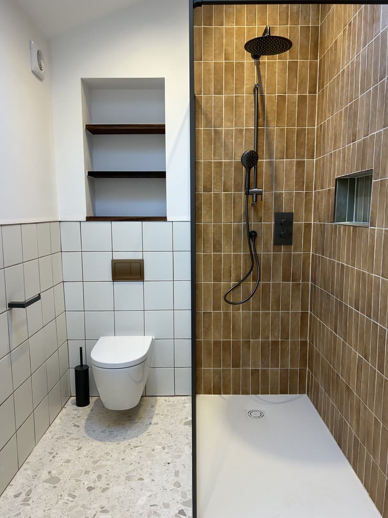 Clay-tiled walk-in shower and wall-hung WC over a terrazzo floor
