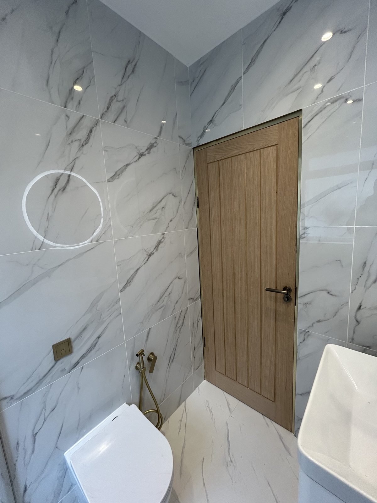 WC and brushed brass fittings against full-height marble-effect porcelain