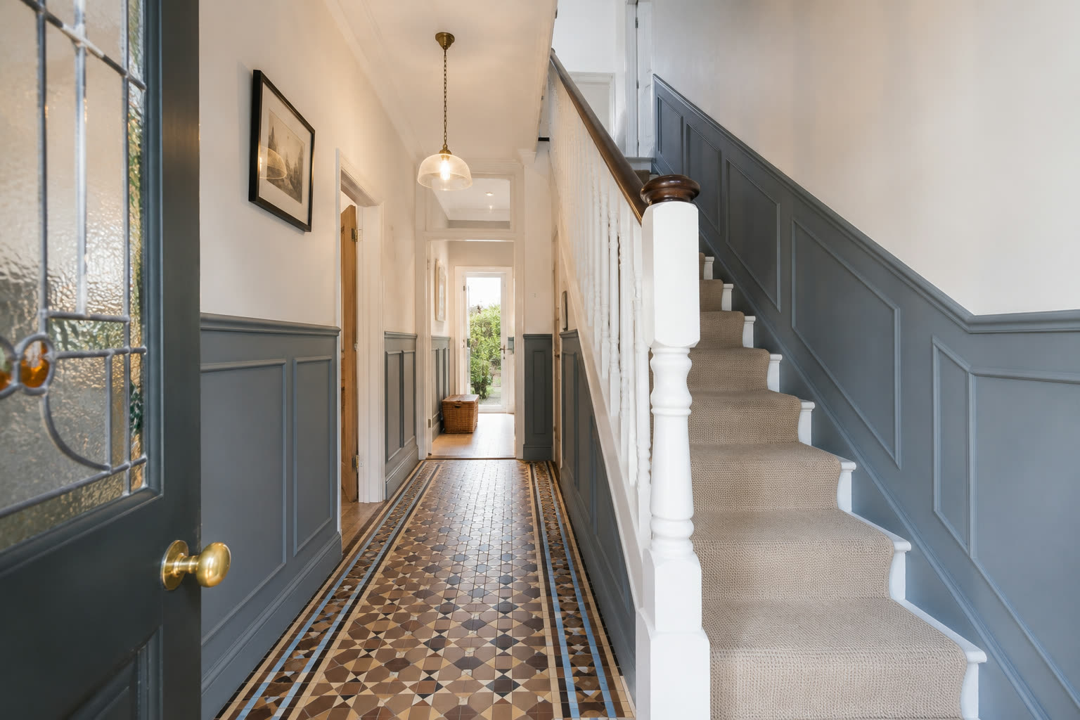 Restored Victorian hallway with a panelled dado, original mosaic floor tiles and a staircase with a runner